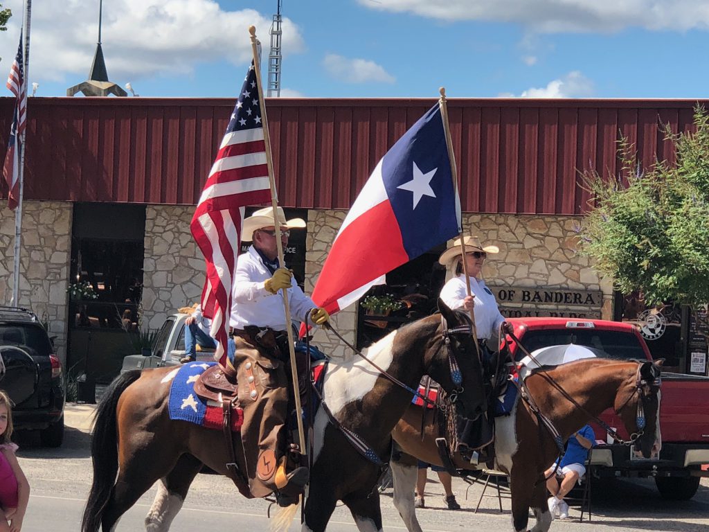 two men on horses carrying the united states and texas state flags