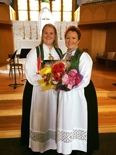 two woman holding flowers and smiling in front of church alter